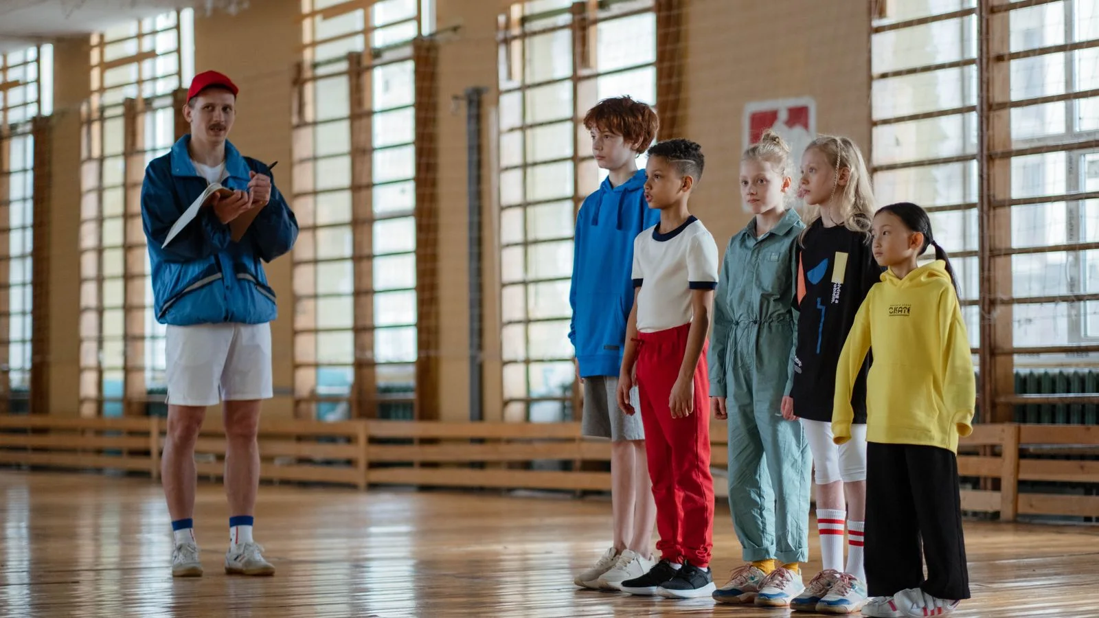 A coach and children standing together in a sports hall
