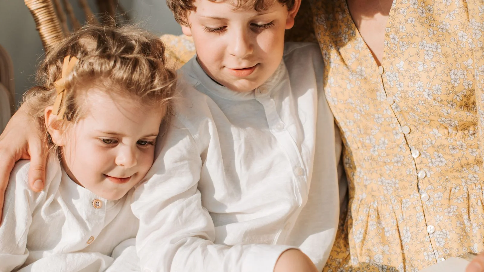 A mother and her children reading a book together on the sofa